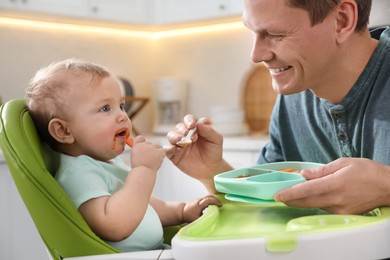 Photo of Father feeding his cute little baby in kitchen