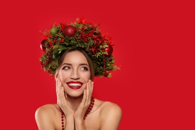 Photo of Beautiful young woman wearing Christmas wreath on red background. Space for text