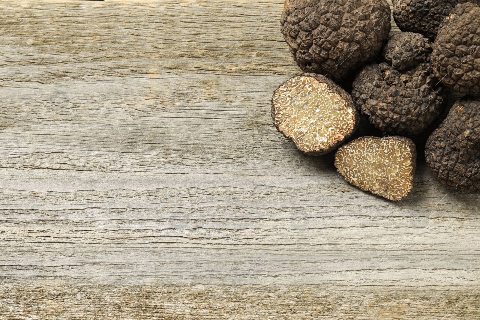 Photo of Black truffles on wooden table, flat lay. Space for text