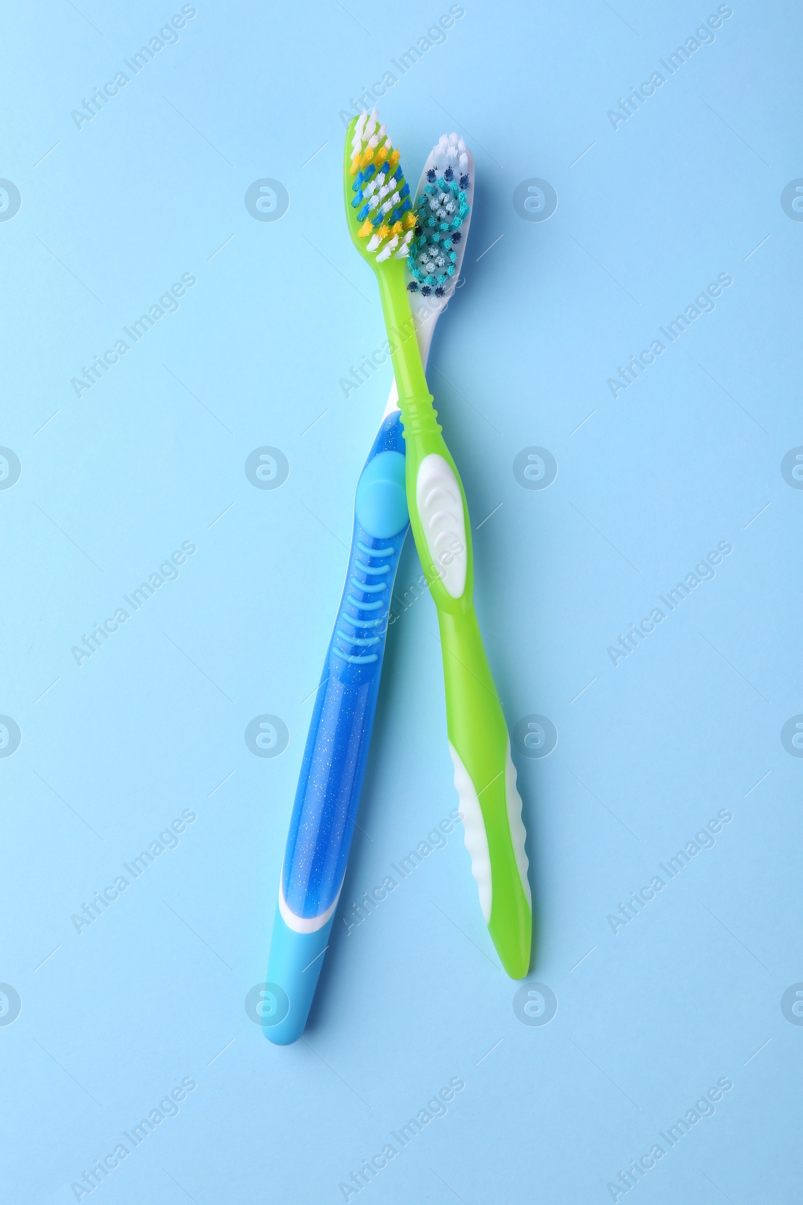 Photo of Two toothbrushes on light blue background, flat lay