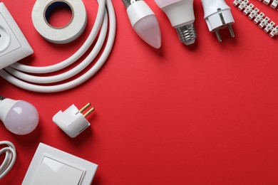 Flat lay composition with electrician's accessories on red background, space for text