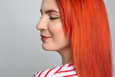 Young woman with bright dyed hair on grey background, closeup