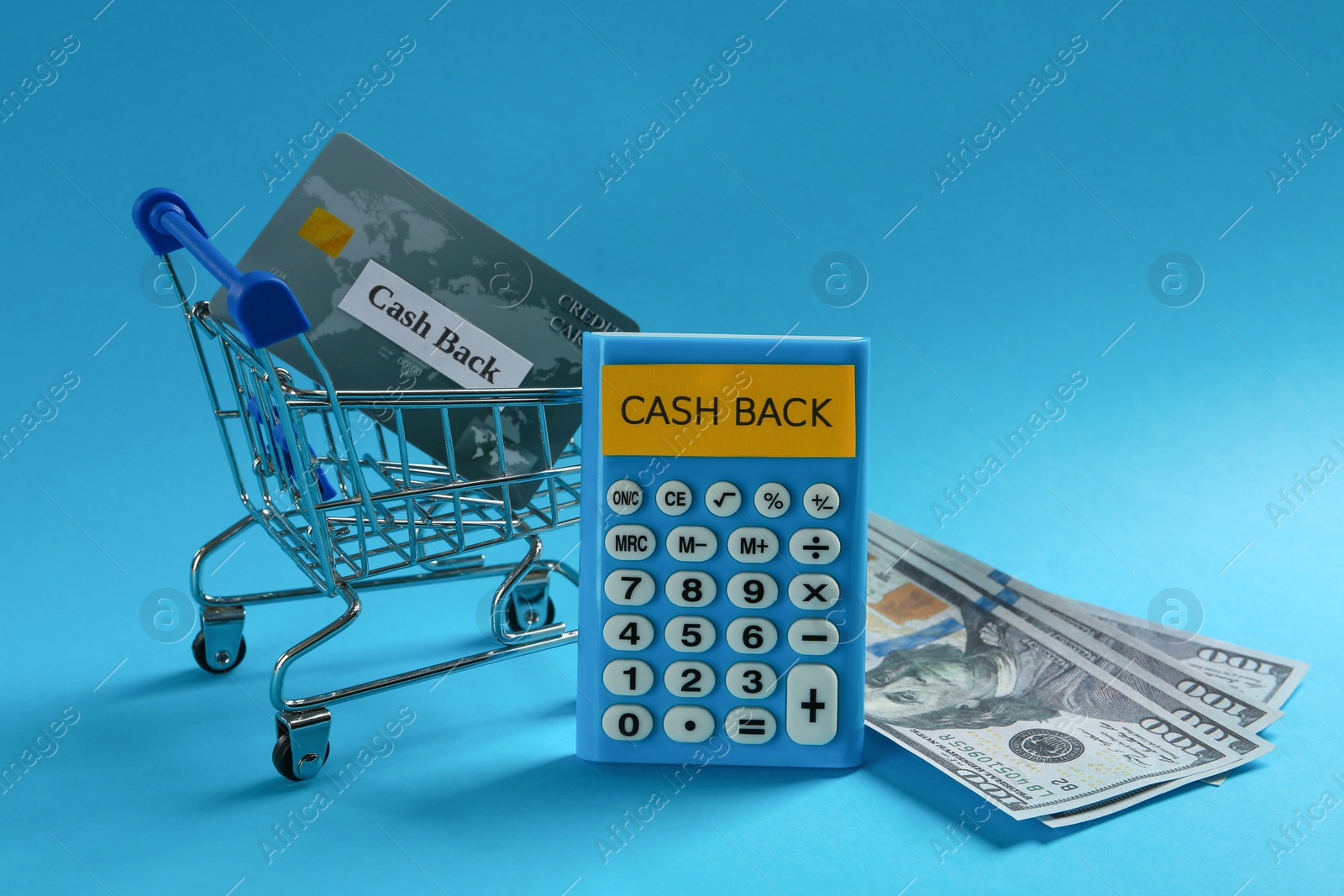 Photo of Calculator, dollar banknotes and credit card in shopping cart on light blue background. Cashback concept
