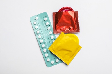 Photo of Condoms and birth control pills on white background, top view. Safe sex concept