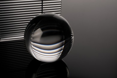 Photo of Transparent glass ball on black mirror surface