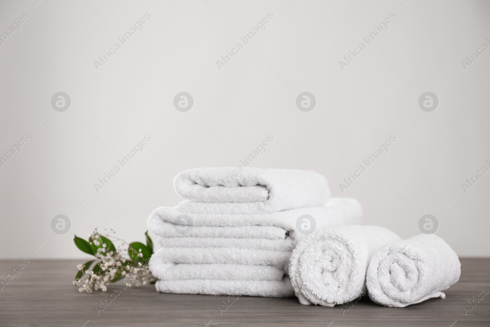Photo of Fresh white towels and green plant on grey wooden table