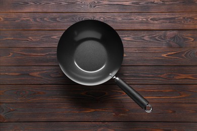 Photo of Empty iron wok on wooden table, top view. Chinese cookware