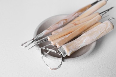 Set of different clay crafting tools on white table