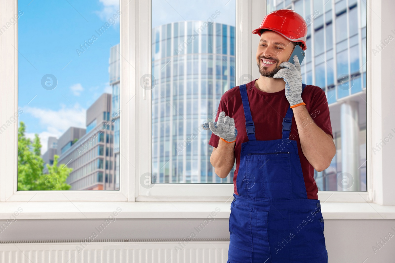 Photo of Professional repairman in uniform talking on phone indoors, space for text