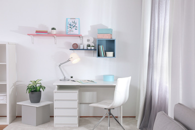 Photo of Stylish room interior with comfortable workplace near window. Design idea