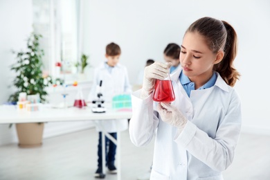 Photo of Schoolgirl holding conical flask at chemistry class