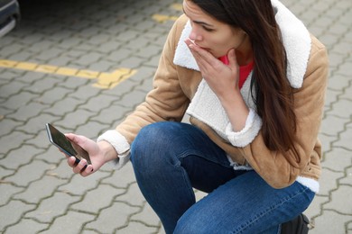 Woman holding damaged smartphone outdoors. Device repairing