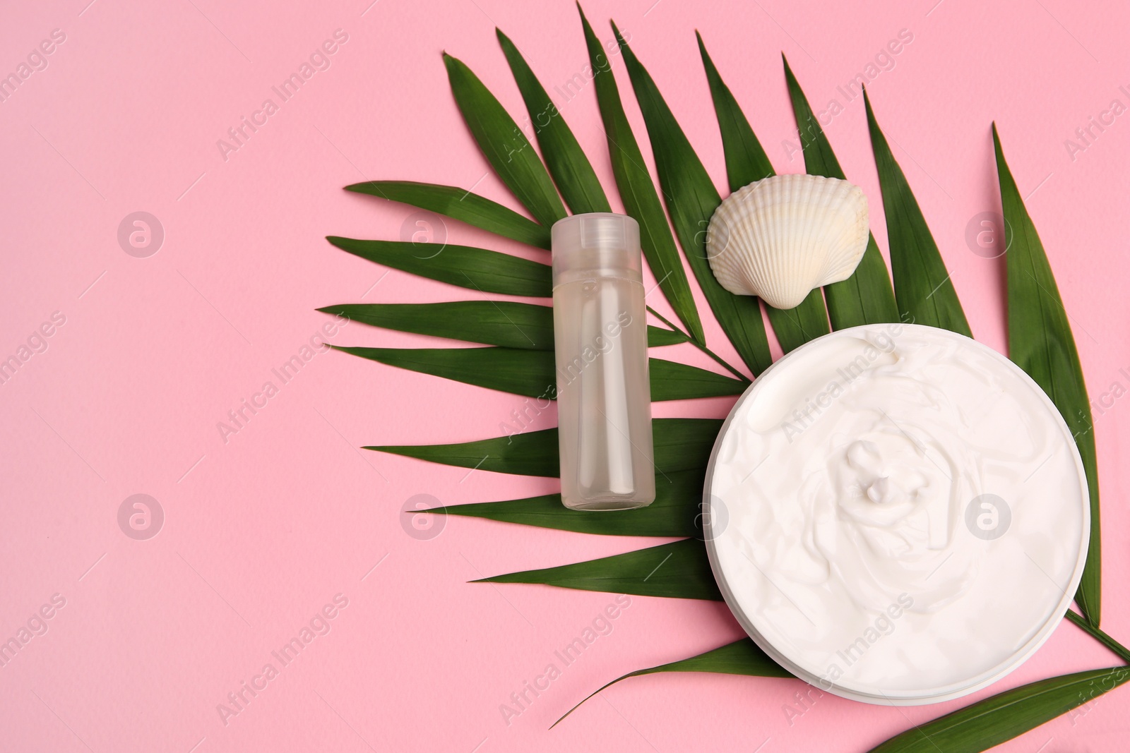Photo of Cosmetic products, palm leaf and shell on pink background, flat lay. Space for text