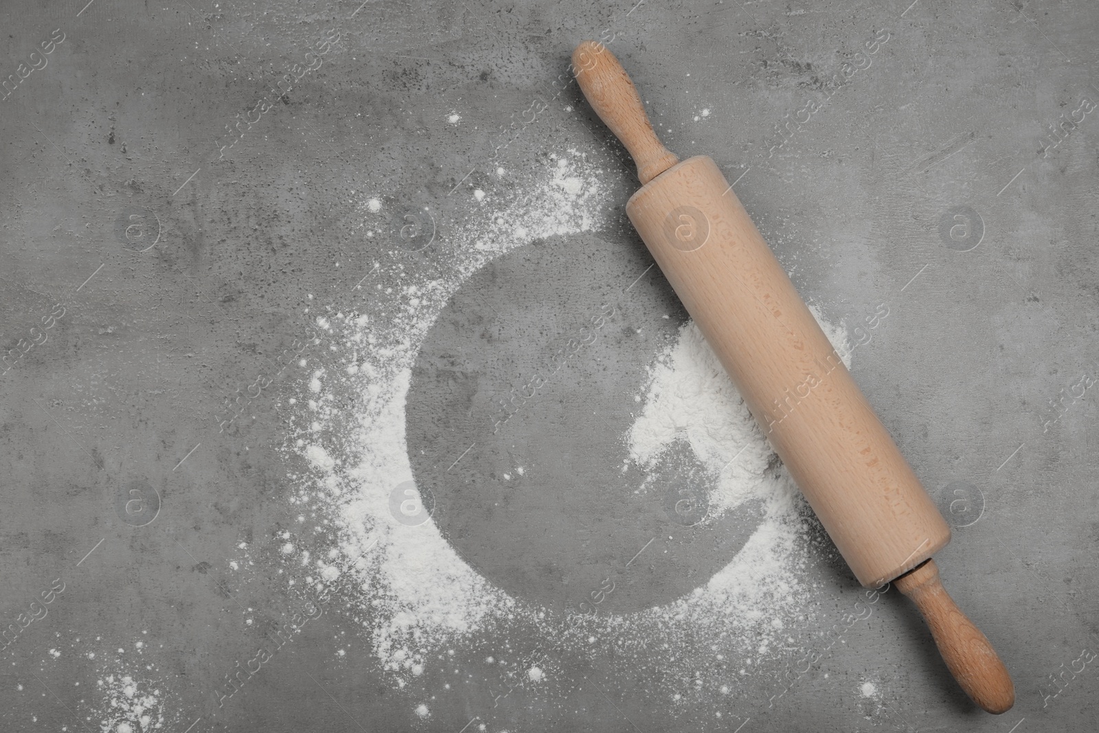 Photo of Flour and rolling pin on light grey table, top view. Space for text