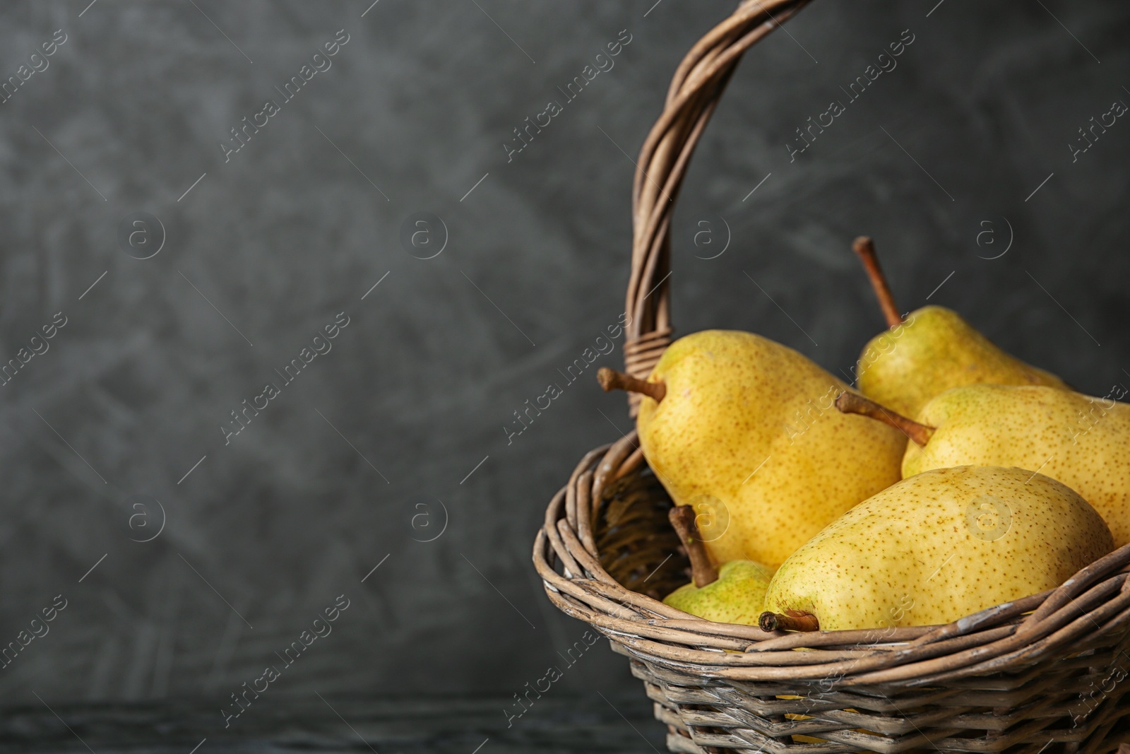 Photo of Basket of fresh ripe pears against gray background with space for text