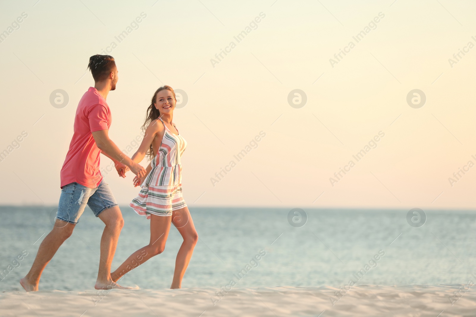 Photo of Happy young couple running together on beach
