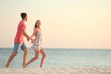 Happy young couple running together on beach