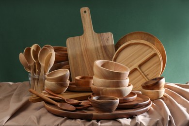 Set of wooden dishware and utensils on table against green background