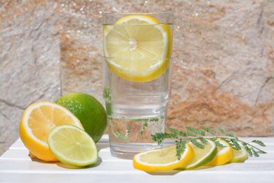 Delicious refreshing lemonade and pieces of citrus on white wooden table outdoors