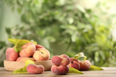 Photo of Fresh ripe donut peaches on wooden table against blurred green background. Space for text