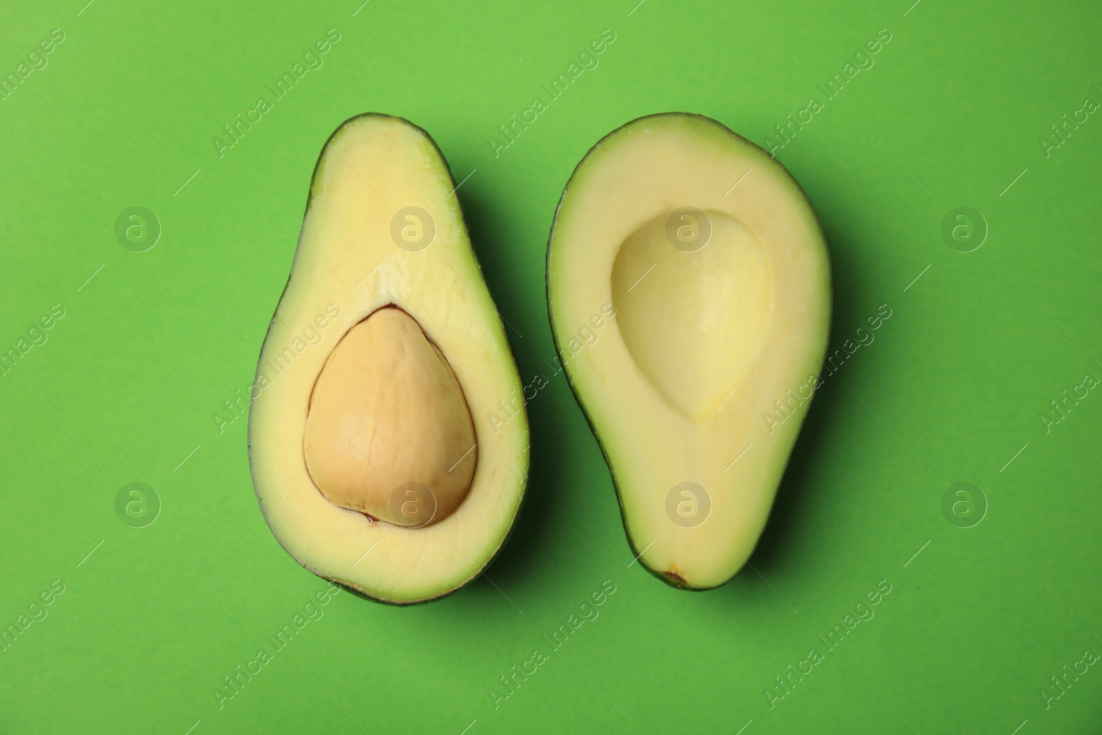 Photo of Cut fresh ripe avocado on green background, flat lay