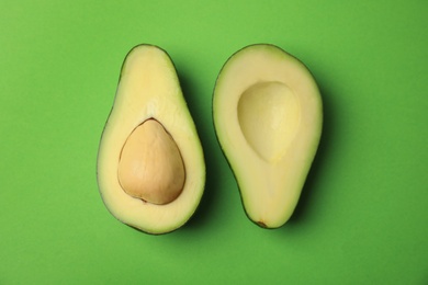 Cut fresh ripe avocado on green background, flat lay