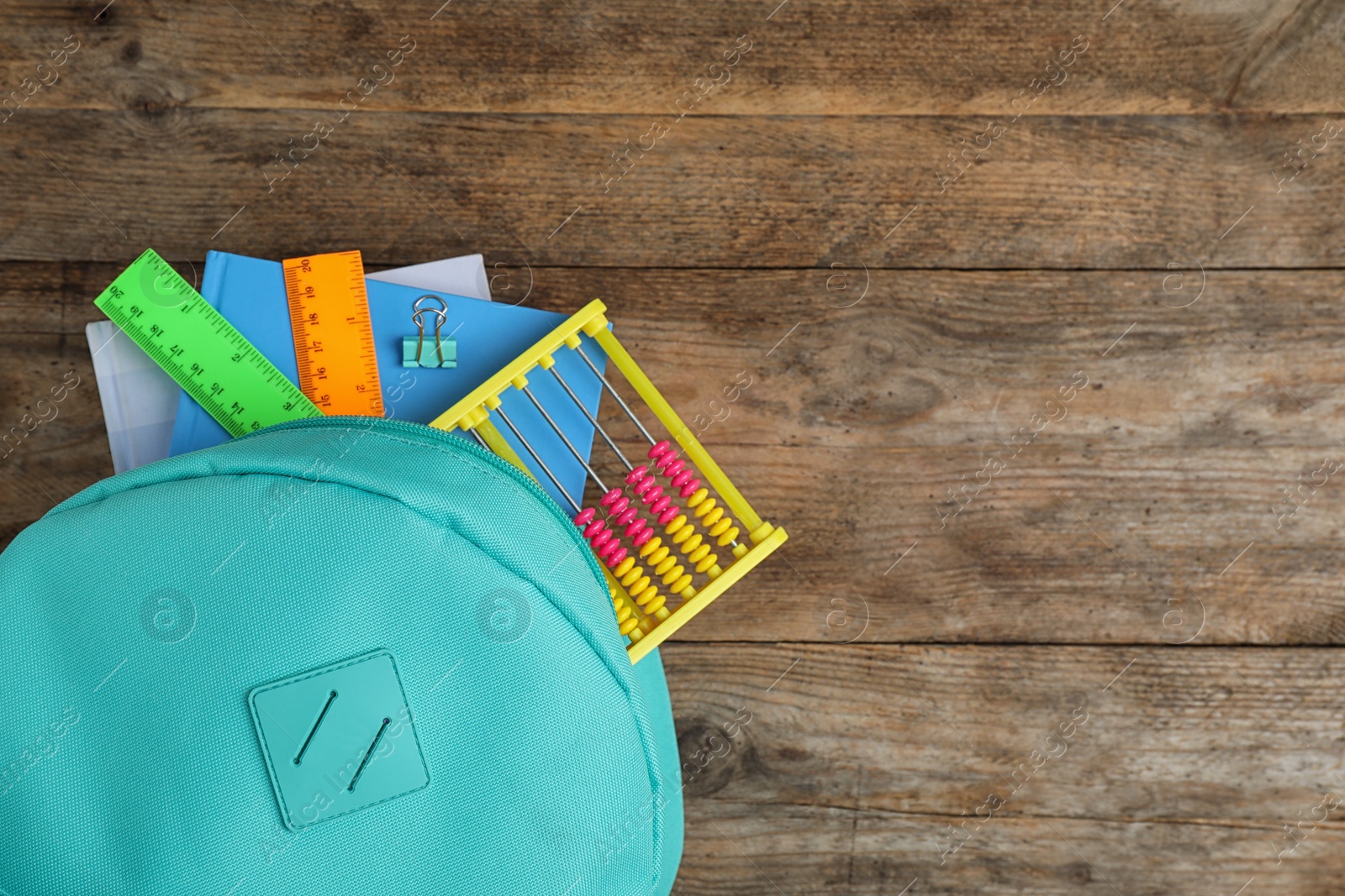 Photo of Stylish backpack with different school stationary on wooden table, top view. Space for text