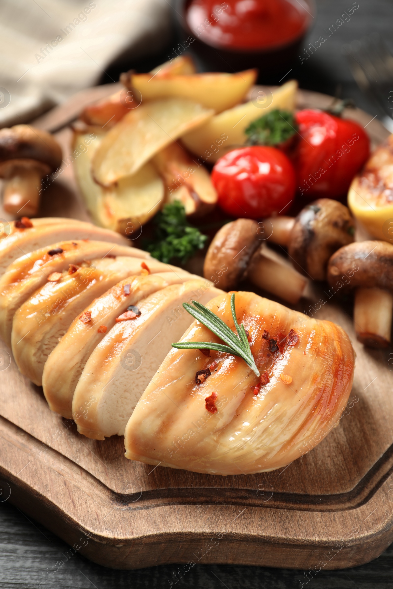 Photo of Fried chicken breast served with garnish on wooden board, closeup