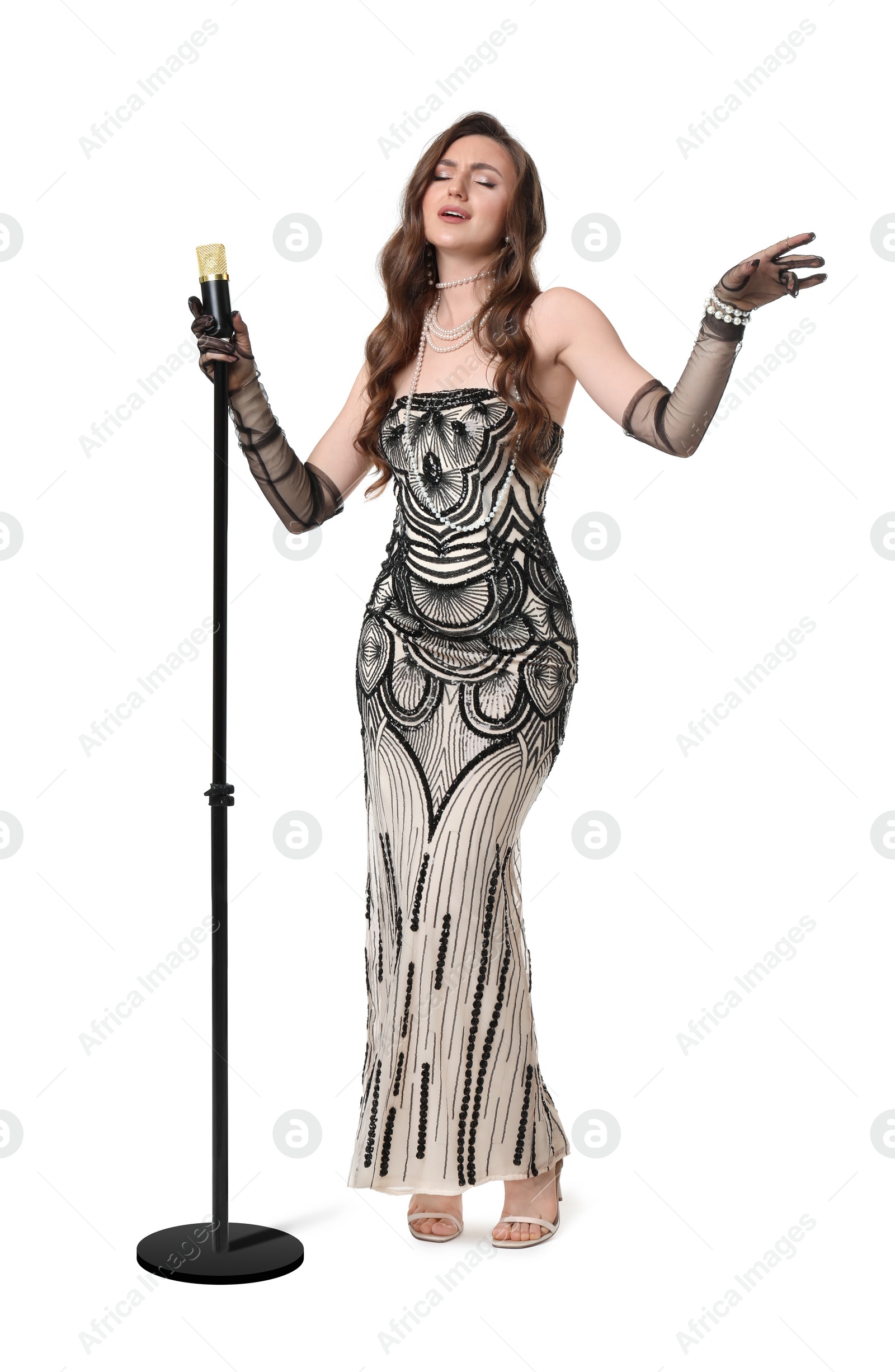 Photo of Beautiful young woman in stylish dress with microphone singing on white background