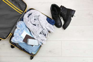 Photo of Packed suitcase on wooden background, top view. Space for text