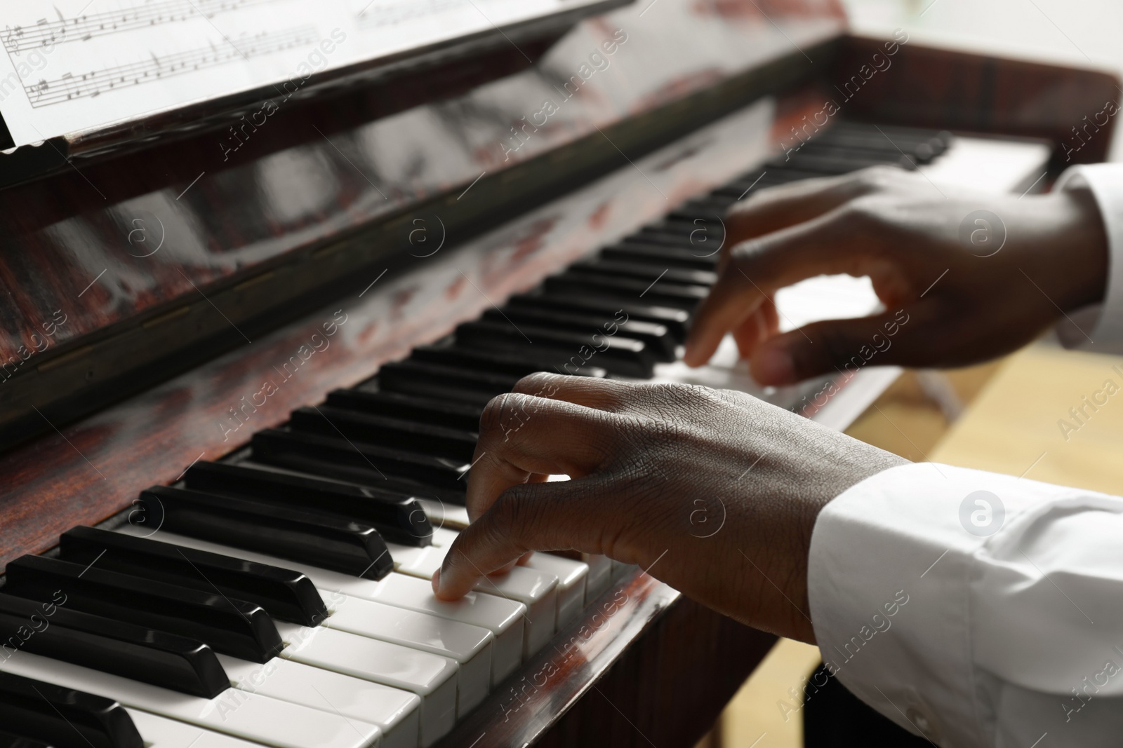 Photo of African-American man playing piano, closeup. Talented musician