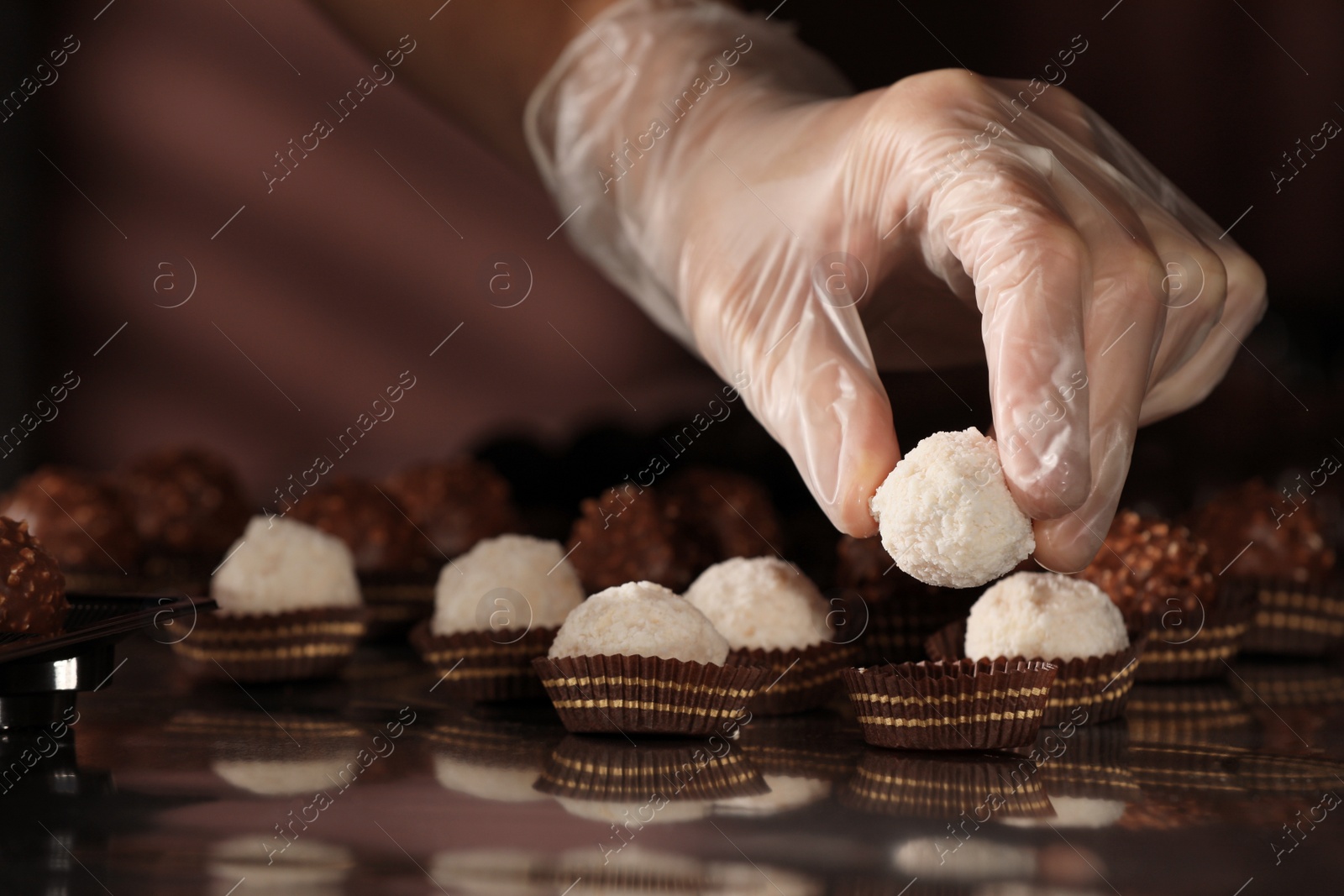 Photo of Woman packing delicious candies at production line, closeup
