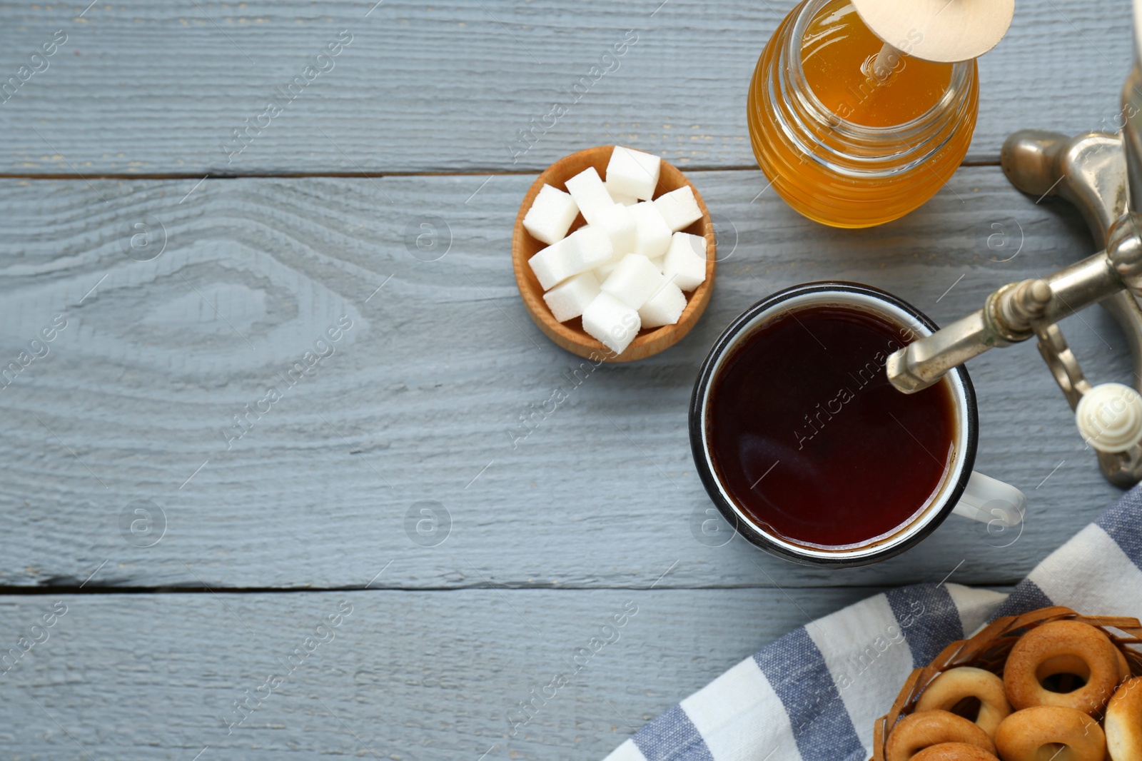 Photo of Flat lay composition with delicious ring shaped Sushki (dry bagels) and mug of tea on light grey wooden table, space for text