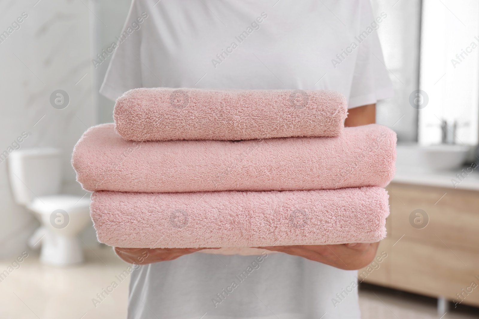 Photo of Woman holding fresh towels in bathroom, closeup