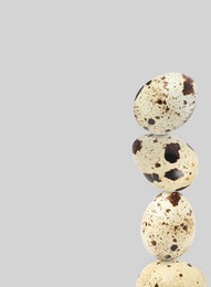 Image of Stacked speckled quail eggs on light grey background. Space for text