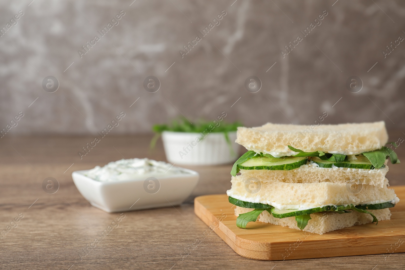 Photo of Board with tasty cucumber sandwiches on wooden table. Space for text