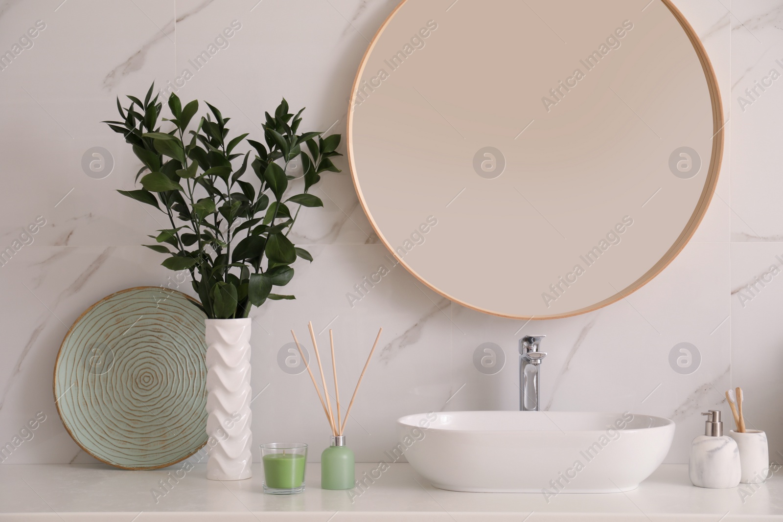 Photo of Vase with beautiful branches and toiletries near vessel sink in bathroom. Interior design