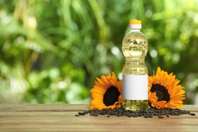 Photo of Sunflower cooking oil, seeds and yellow flowers on wooden table outdoors, space for text