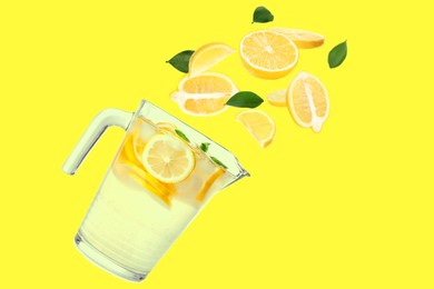 Image of Glass jug with natural lemonade, fruits and green leaves flying on yellow background