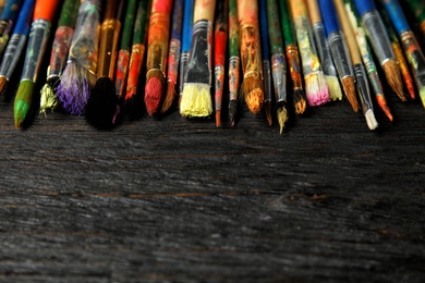 Different paint brushes on wooden table, closeup. Space for text