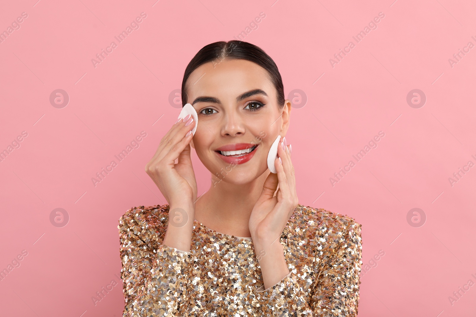 Photo of Beautiful woman removing makeup with cotton pads on pink background