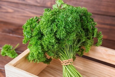 Wooden crate with fresh green parsley on table, closeup