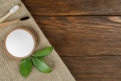 Bamboo toothbrushes and bowl of baking soda on wooden table, top view. Space for text