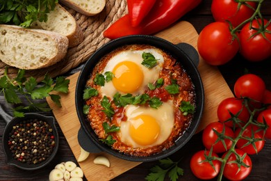 Photo of Flat lay composition with delicious shakshuka in frying pan on wooden table
