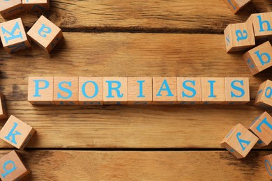 Word Psoriasis made of cubes with letters on wooden table, flat lay