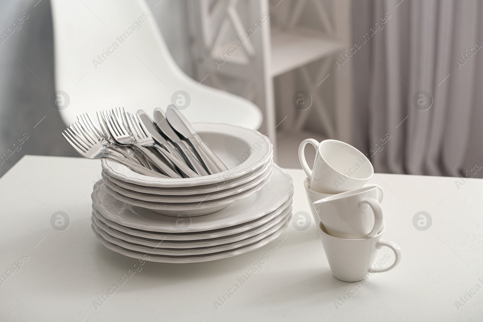Photo of Set of clean dishware and cutlery on white table indoors