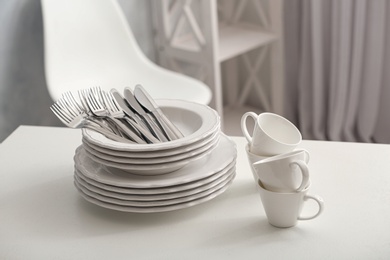Set of clean dishware and cutlery on white table indoors