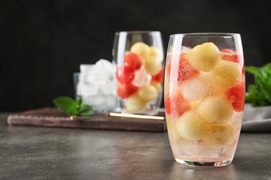 Photo of Glass of melon and watermelon ball cocktail on grey table. Space for text