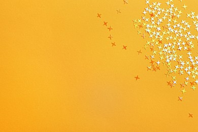 Shiny bright glitter on light orange background, flat lay. Space for text