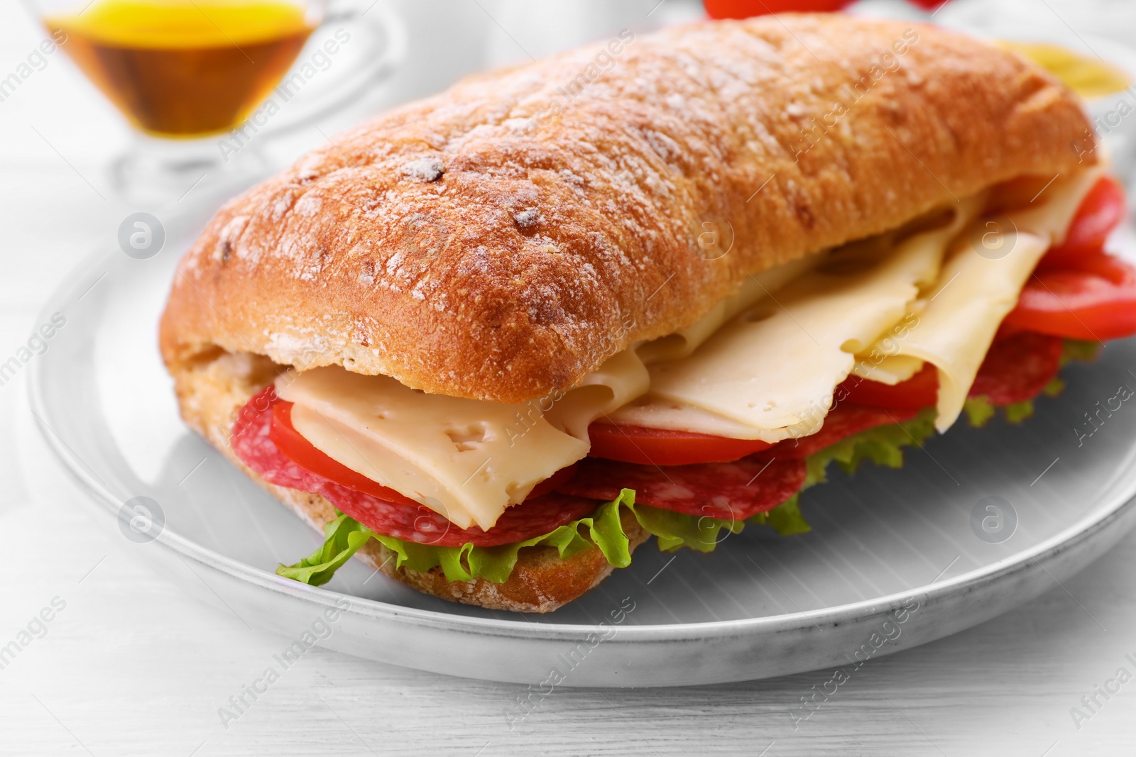 Photo of Delicious sandwich with cheese, salami, tomato on white wooden table, closeup